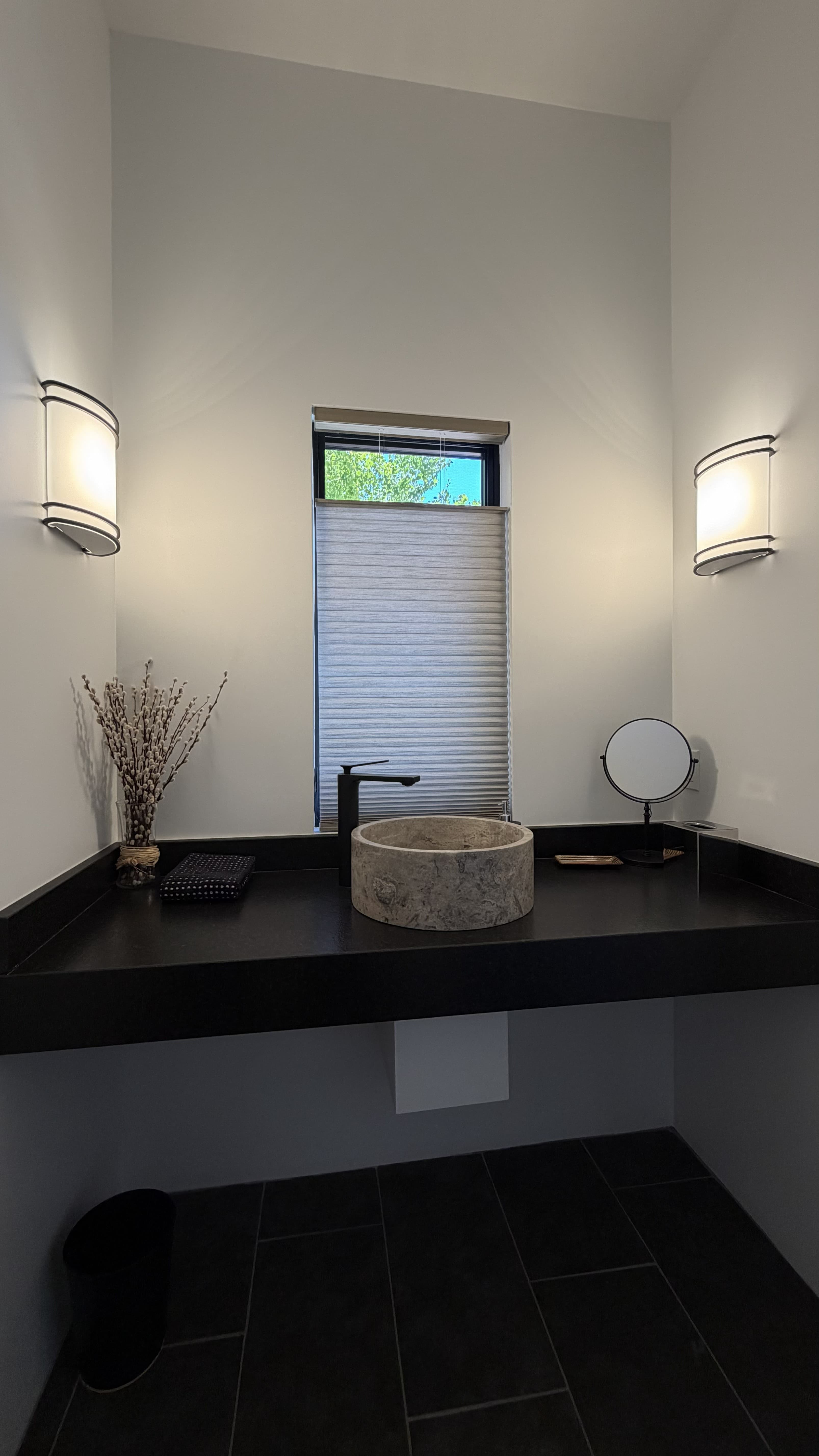 Powder room: stone vessel sink on a black counter.